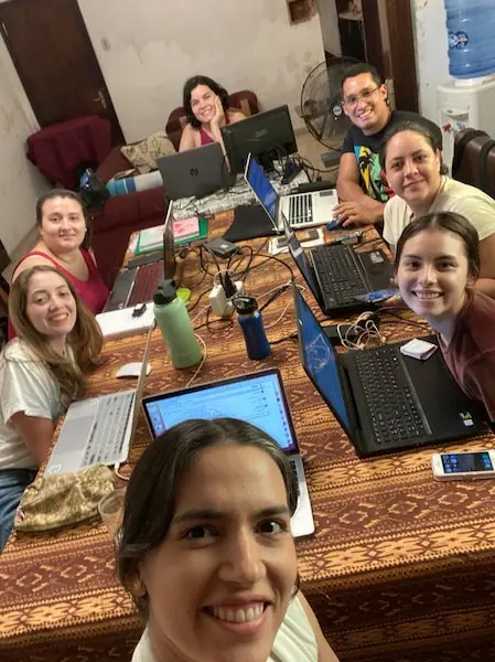 Selfie de Aura con el equipo de Gánica trabajando con sus computadoras alrededor de una mesa