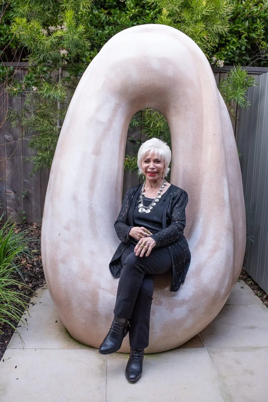 Isabel Allende sentada dentro de una escultura blanca en un jardín
