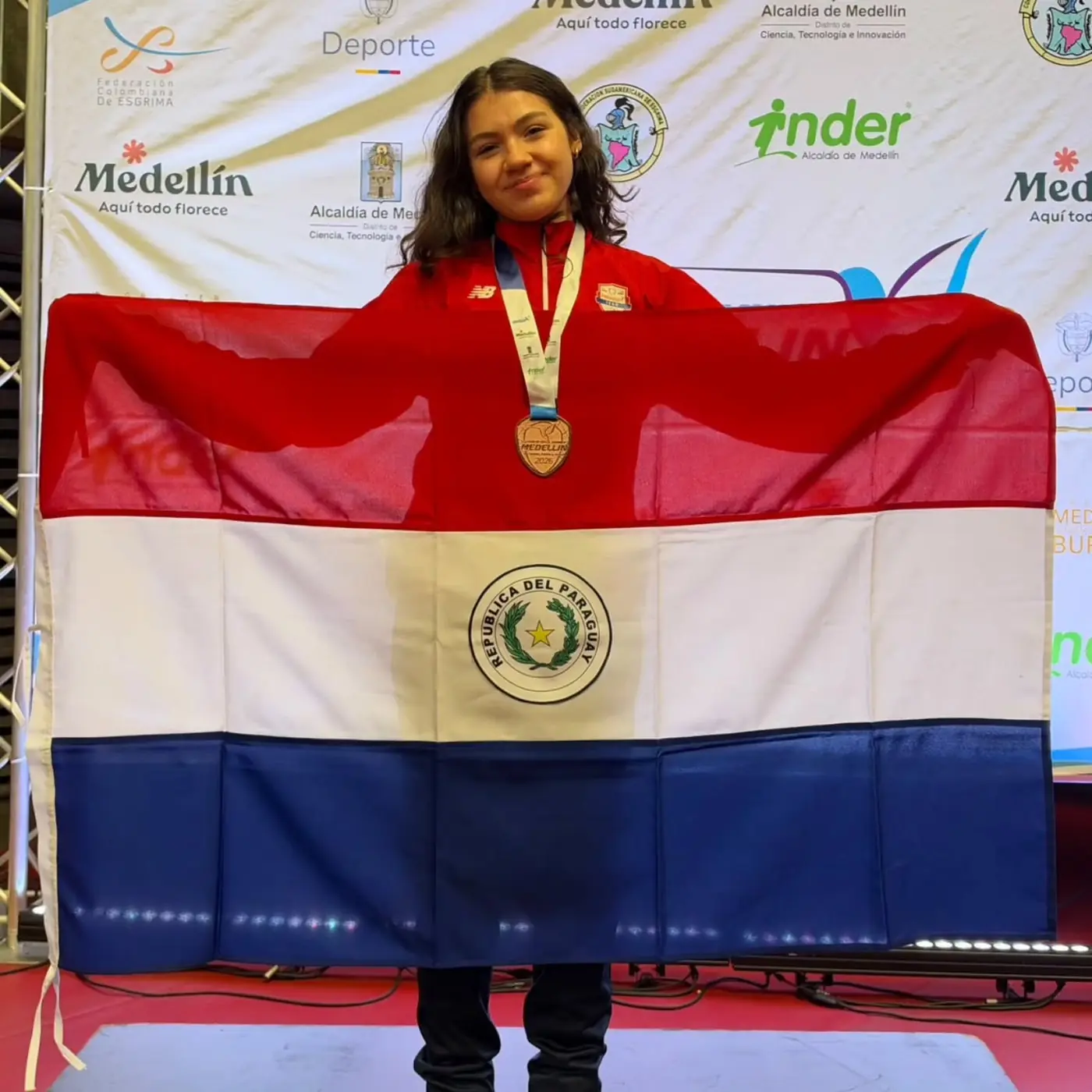 Lía Lombardo con la bandera paraguaya y su medalla en el podio de Medellín