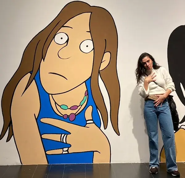 Aura posa junto a un gran mural de un personaje de Maitena