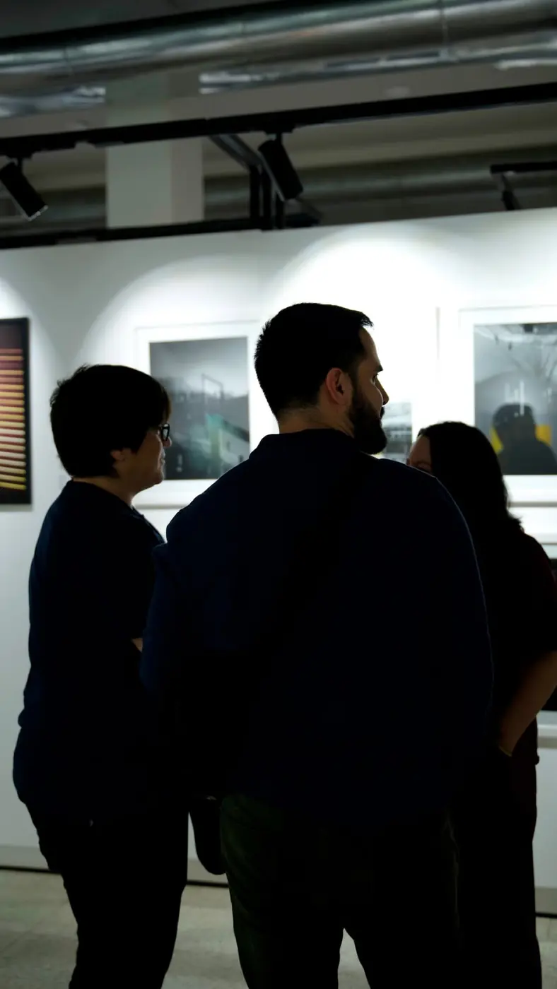 Un grupo de personas conversa frente a fotos de paisajes en una sala blanca