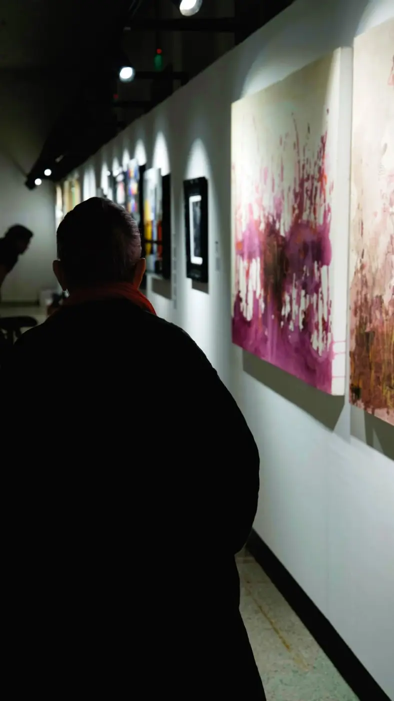 Un hombre recorre un pasillo con cuadros abstractos grandes en fucsia y magenta