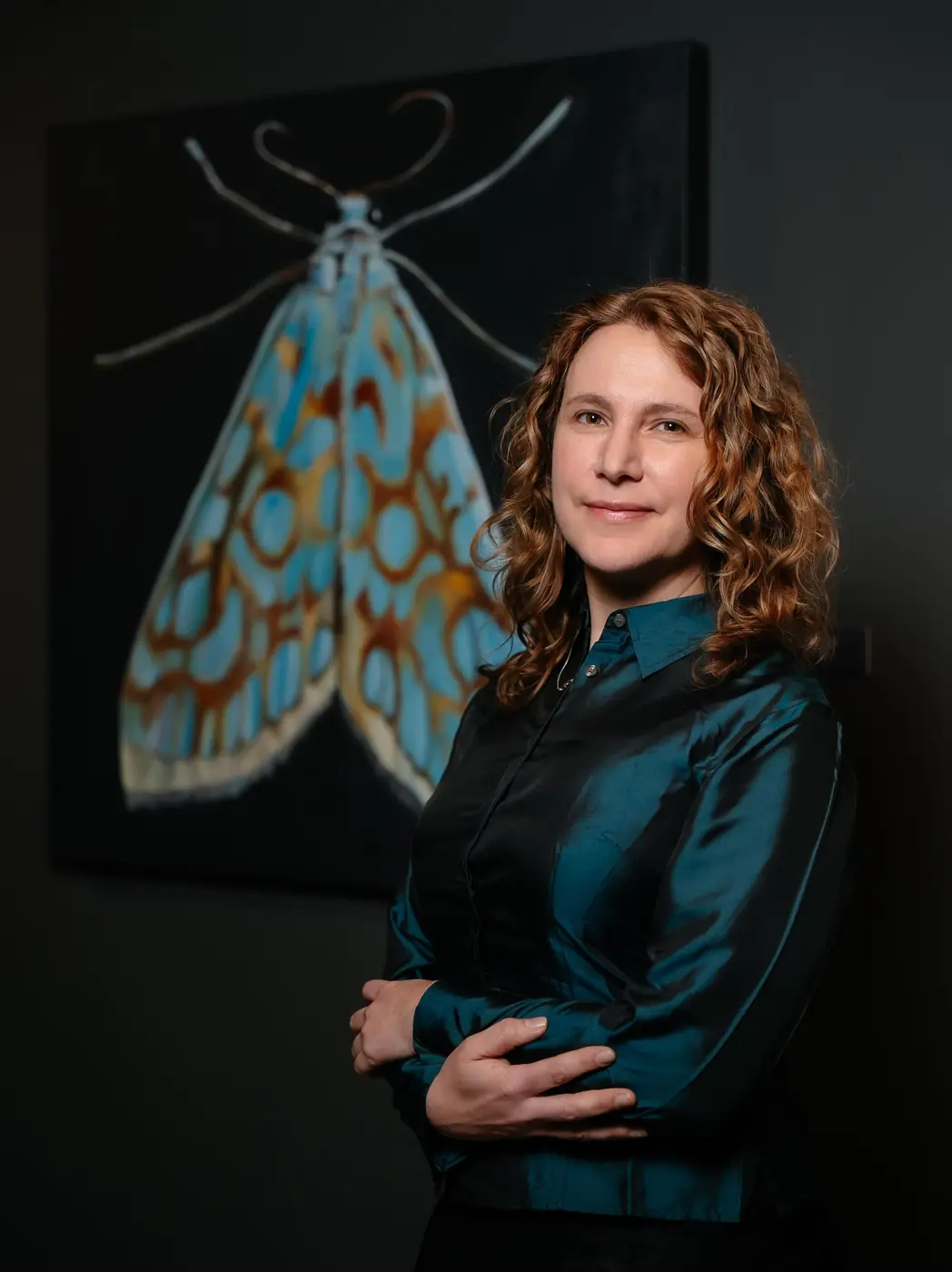 Silvana Nuovo de brazos cruzados delante de una pintura de una polilla celeste